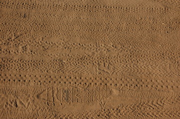 background traces of shoes and bicycle tires on the beige sand