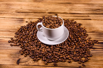 White cup filled with coffee beans on wooden table