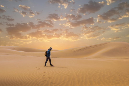 A man travel in the desert by walking . 