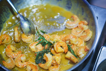 Creative serving of seafood during at event. Top view on cooked shrimps in a sauce in a pan.
