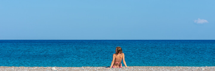 Wide view image of young woman in pink bikini sunbathing