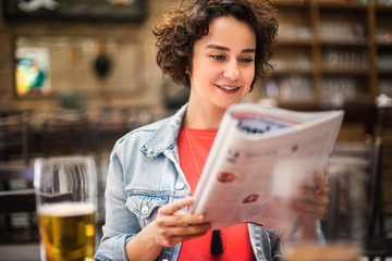 Girl at a coffee shop going through newspapers. Teen searching for a job in newspapers.