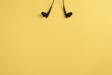 Black headphones on a yellow background Flat lay top view