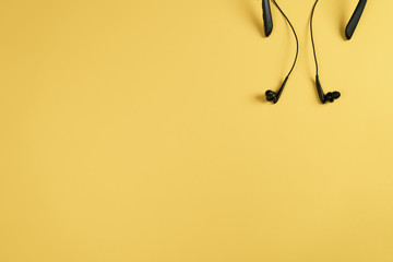 Black headphones on a yellow background Flat lay top view