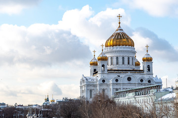 Fototapeta premium winter view of the snow-covered Golden domes of the Cathedral of Christ the Saviour with white walls against the cloudy sky