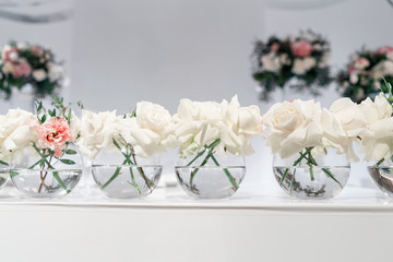 Small flower arrangements in ball glass vases. The table of the newlyweds. Interior of restaurant for wedding dinner, ready for guests. Catering concept.