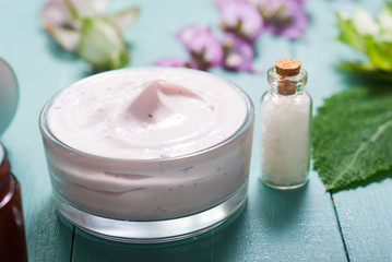 cosmetic creams and clary flowers on blue wooden table