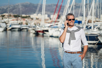 Senior man talking on the smartphone on the marina