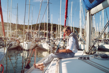 Senior man is working during the vacation on a sailboat