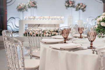Flower arrangement in the center of the table. Interior of restaurant for wedding dinner, ready for guests. Round Banquet table served. Catering concept.