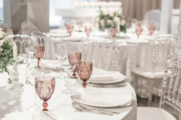 Round Banquet table served. Interior of restaurant for wedding dinner, ready for guests. Decorated with floral arrangement. Dishes, wine glasses and napkins. Catering concept.
