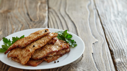roast meat in a plate on a wooden table. with free text space
