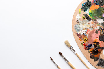 Colorful painter's palette and brushes on white background.