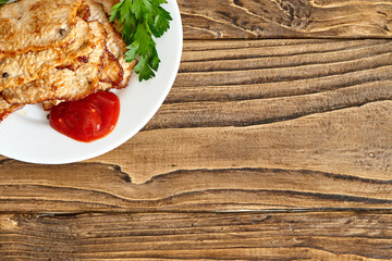 roast meat in a plate on a wooden table. shot from above. with free text space