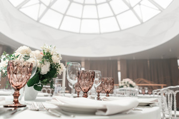 Flower arrangement in the center of the table. Interior of restaurant for wedding dinner, ready for guests. Round Banquet table served. Catering concept.