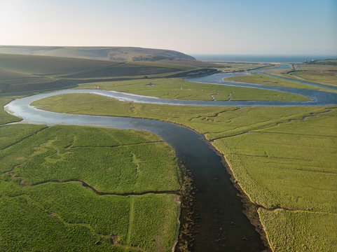Stunning aerial drone landscape image of meandering river through marshland at sunrise