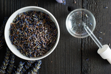 perfume, essential oil, soap and dried lavender flowers on black wood table background