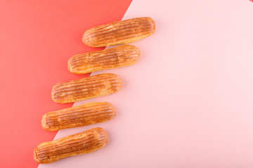 Tasty and beautiful eclairs on a colored background. Delicious dessert