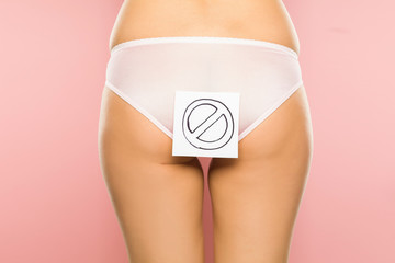 Woman holding prohibition sign in front of her buttocks
