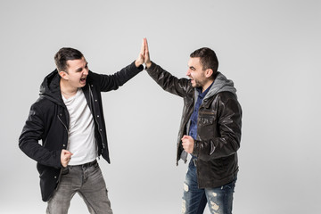 Portrait of two happy young men giving high five isolated over white background