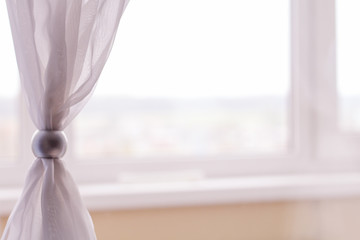 light beige curtains are decorated with a decorative ring. comfort in the room.