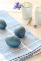 Naturally dyed Easter eggs and blue flowers on a white wooden table