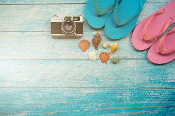 Flat lay design of travel to the sea concept with camera, hat, sandals and shell on blue wooden background.