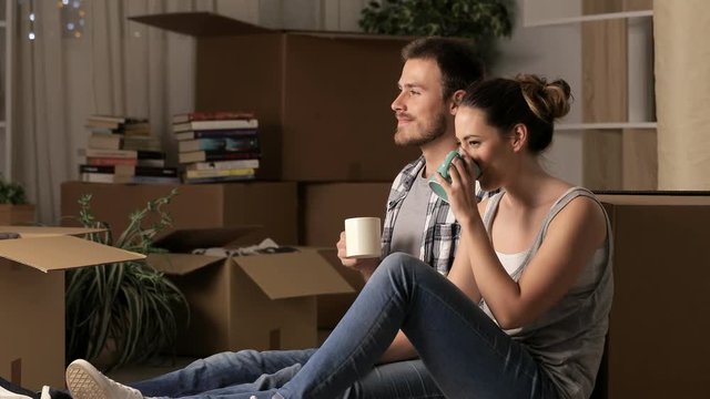 Couple moving home resting drinking coffee sitting on the floor at home