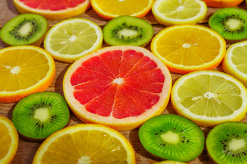 Fototapeta na wymiar frame with slices of oranges, lemons, kiwi, grapefruit pattern on wooden background. Copy space