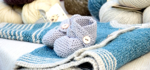 Fototapeta na wymiar Babyschuhe und Babyjacke handgestrickt aus feiner Merinowolle - Babys kuschelige Erstausstattung