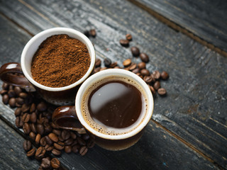 A Cup of ground coffee and a Cup of espresso on a dark wooden table