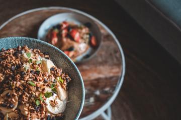 Bright plate with a healthy summer Breakfast American pancakes with berries and a power bowl made of natural yogurt cereal and banana on a wooden background