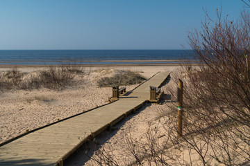 New wooden road leading from the beach dune forest with pines and white sent to the Baltic Sea gulf - Vecaki, Latvia