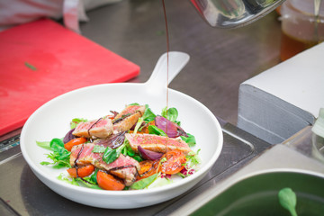 the chef prepares a fresh salad with tomatoes and vegetables, grilled fish