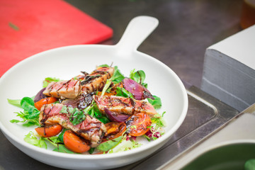 the chef prepares a fresh salad with tomatoes and vegetables, grilled fish