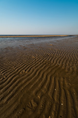 Fototapeta na wymiar Dessert like textured sand - Baltic sea gulf beach with white sand in the sunset