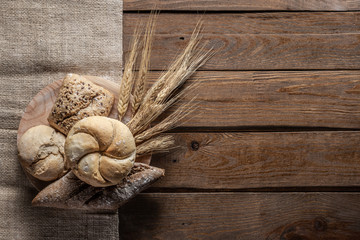 bread with wheat ears and flour on wood board, top view
