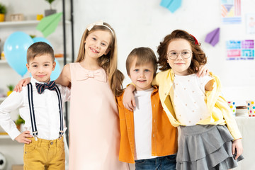 adorable kids looking at camera and hugging at home