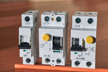 Electric circuit breaker, protective shutdown device, differential current circuit breaker lie in a row on the table. Devices to protect homes and buildings from short-circuit currents and human life.