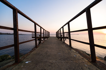 Fototapeta premium Lighthouse during a last minute of sunset with a big sun close to the horizon and clear sky