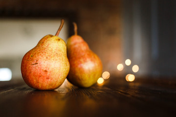 Beautiful ripe tasty pears on a large kitchen wooden table with a garland of lights. A beautiful...