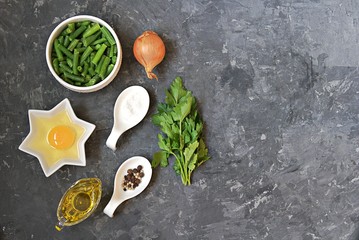 Ingredients for cooking green asparagus beans with scramble egg: raw green asparagus beans, egg, onion, salt, pepper, parsley, oil. Georgian cuisine. Top view, copy space.