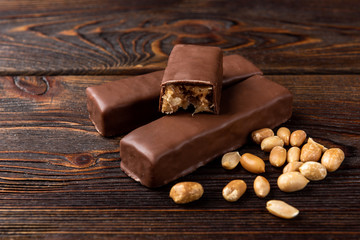 Chocolate bar with caramel and peanut on dark wooden background. 