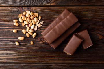 Chocolate bar with caramel and peanut on dark wooden background. 