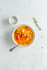 View from above on spring vegetable soup with chicken stock for one person on white table.