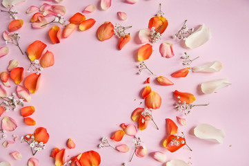 Orange, rose, and white roses petals on the pink background