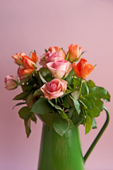 Beautiful pink and orange roses in a vase on the vintage background