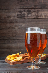 Glass beer and snacks against wooden background