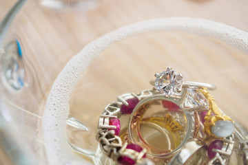 cleaning vintage jewelry diamond ring and bracelet in glass on wood table background