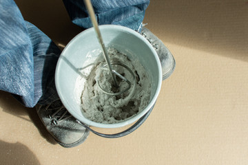 Fototapeta premium Man builder mixes gypsum putty in a bucket